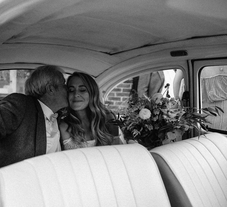 Bride in Grace Loves Lace bardot wedding dress holding mixed bridal bouquet sits in the back of VW bug with man in suit before Isle of Wight wedding