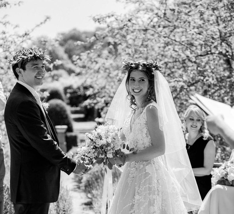 Bride & groom hold hands during wedding ceremony in black & white image