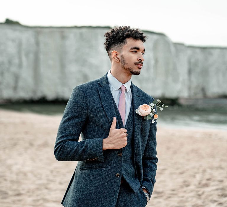 Stylish groom in a three-piece blue wool suit and light pink satin tie 