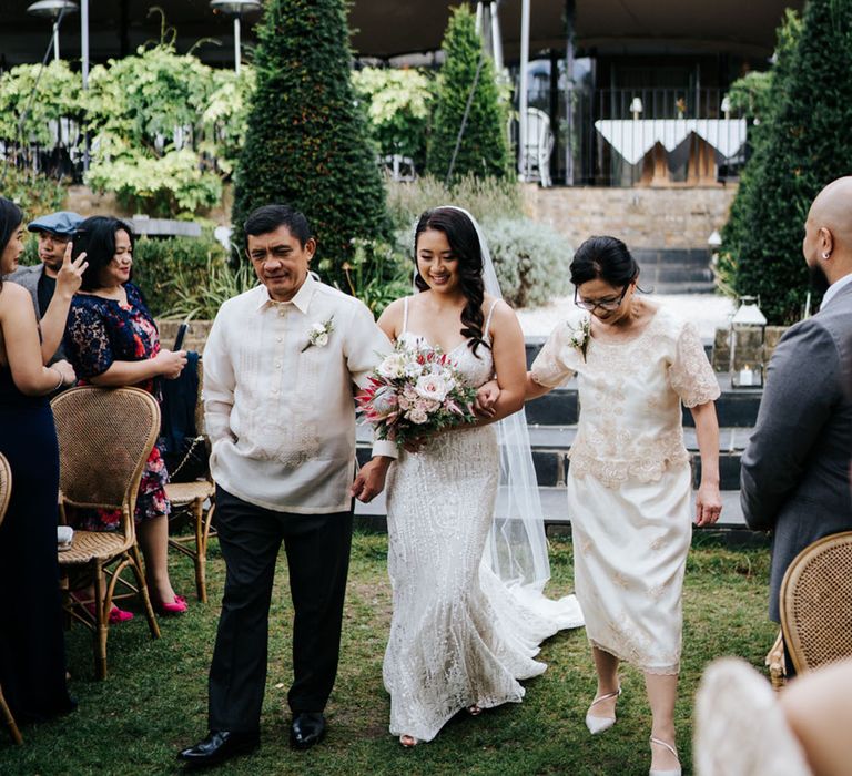 Mother and Father of the bride walk Bride down the aisle in elegant sparkly long wedding dress