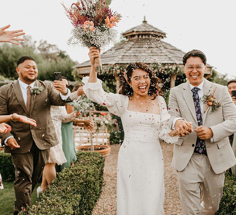 Bride & groom celebrate as bride holds homemade floral bouquet