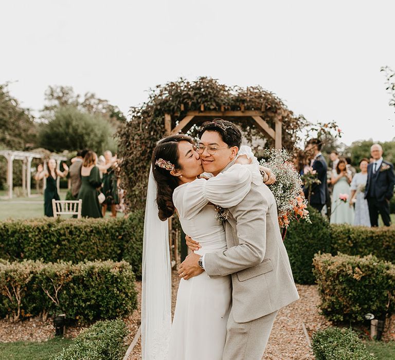 Bride & groom hug outdoors on their wedding day at the Secret Garden wedding venue