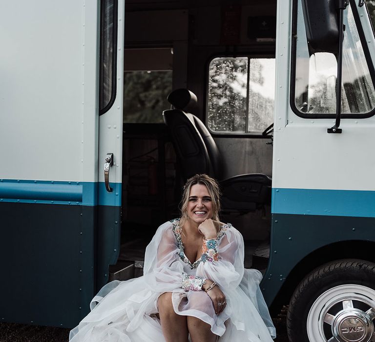 Smiling bride in bespoke Victoria Sanders wedding dress and white Nike Air Max trainers sits in van at Iscoyd Park