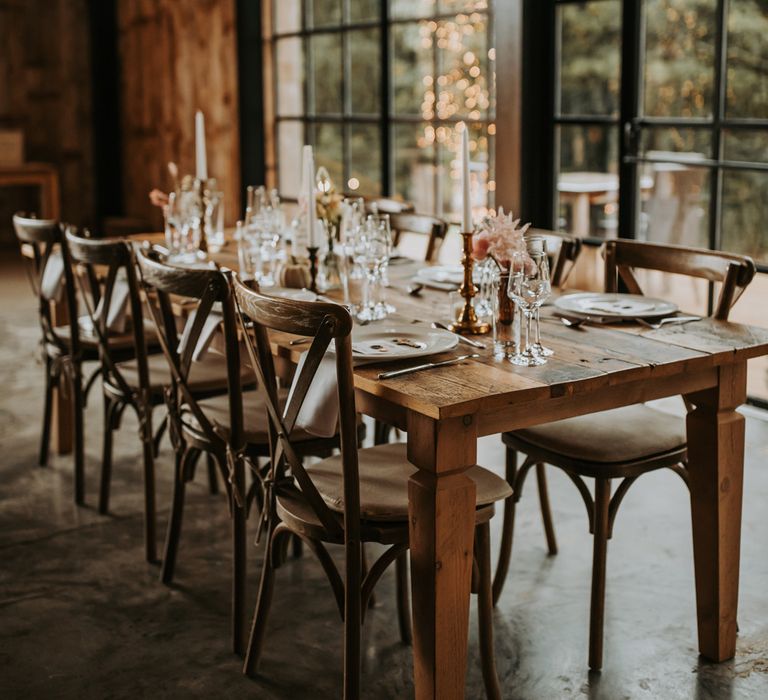 Rustic wooden wedding table with dinner candles, dried florals and glassware for Lake District barn wedding