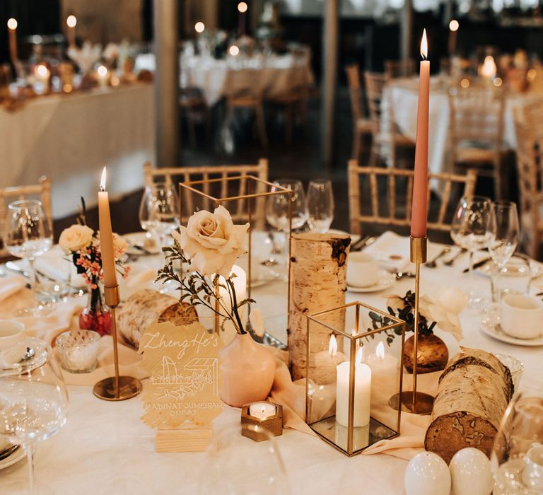 White round wedding tables with roses, candles and pink dinners candles at Industrial wedding venue