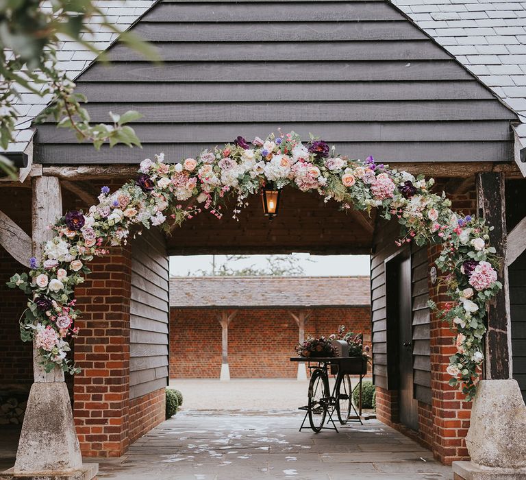 Country house venue with flower arch made up of assorted flowers and colours