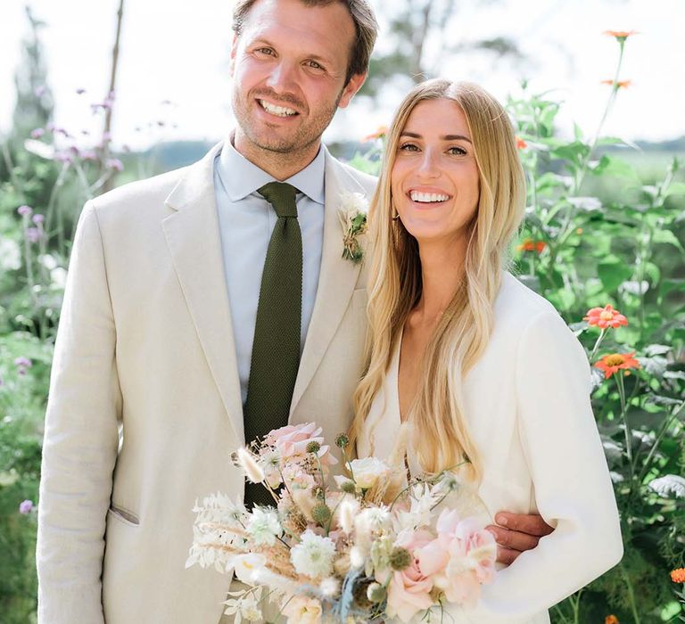 Bride and groom smile at the camera together at their summer garden wedding in Bath