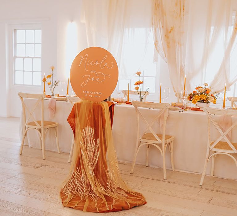 intimate golden wedding table scape with drapes and linens and orange wedding sign 