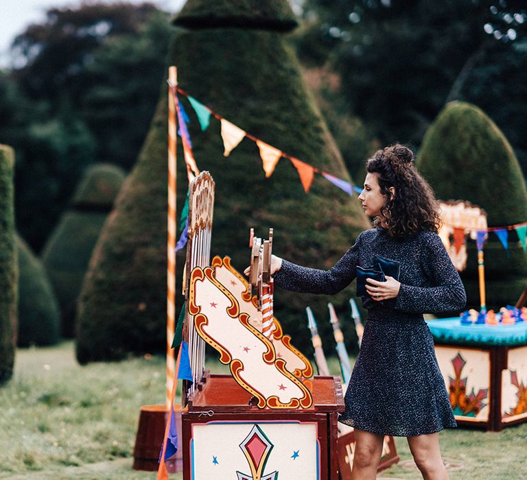 Wedding guest plays fairground games at wedding with colourful bunting at Askham Hall