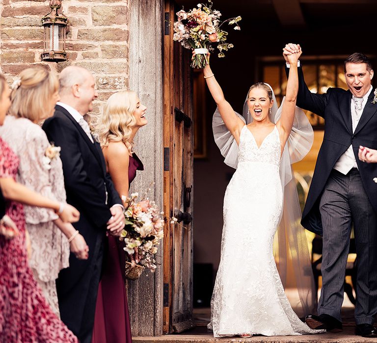 Bride and groom raise their arms as they exit their wedding ceremony as a married couple 