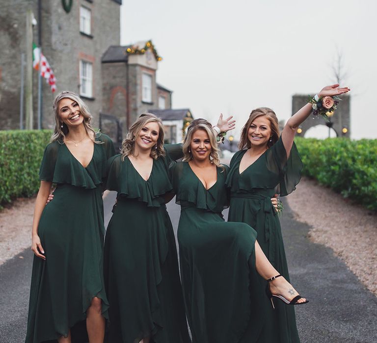 Bridesmaids in forest green ruffle wrap dresses with matching corsages 