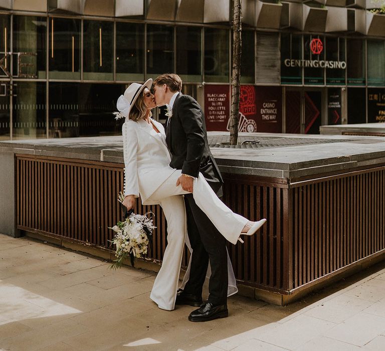 Bride and groom kiss as he lifts the bride's leg