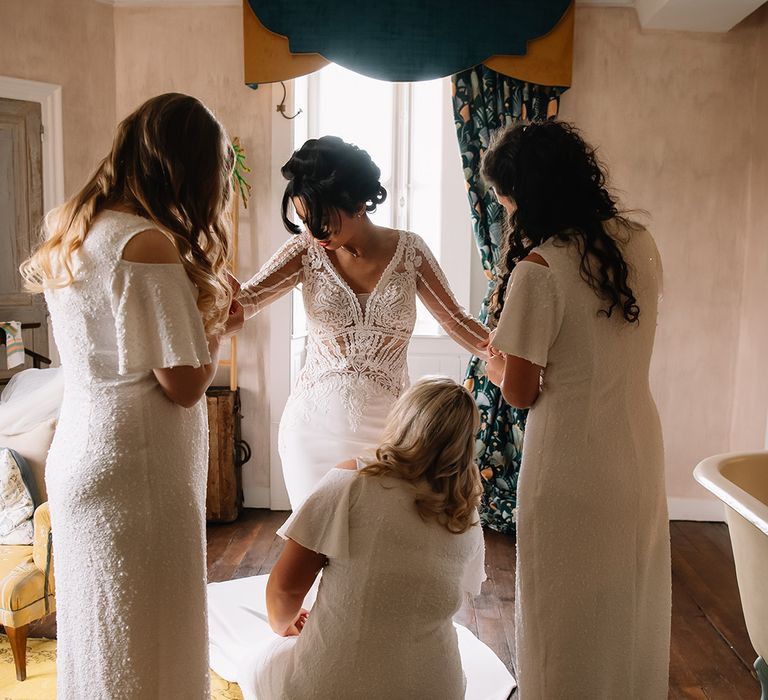 Bridesmaids help the bride get ready for the big day with finishing touches 