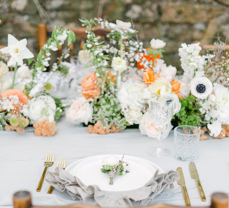 place setting with linen napkin, white tableware and peach wedding flowers 