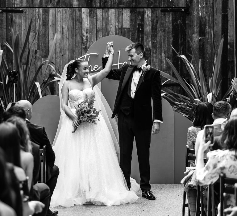 Bride & groom celebrate after wedding ceremony in front of DIY altar at the 100 Barrington in black & white image