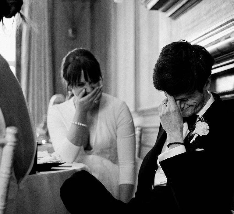 Bride & groom laugh during intimate moment in black & white image 