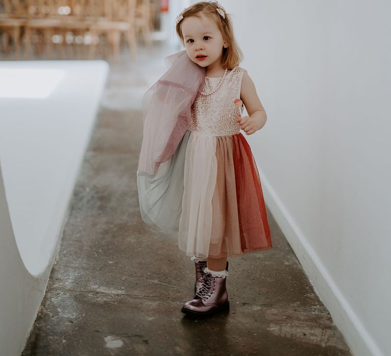 Flower girl wears multicoloured dress complete with purple boots 