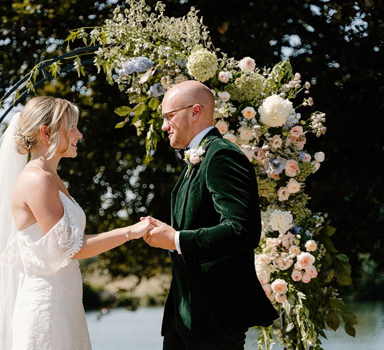 Groom wears green velvet black tie whilst marrying his bride in outdoor ceremony 