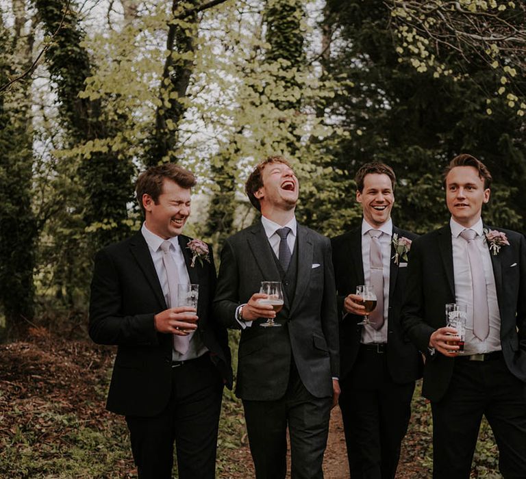 Groom in a dark grey three piece suit with groomsmen in dark suits and pale purple ties 