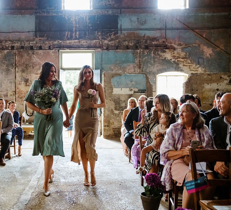 Bridesmaids in mismatched dresses walk down the aisle at The Asylum Chapel 