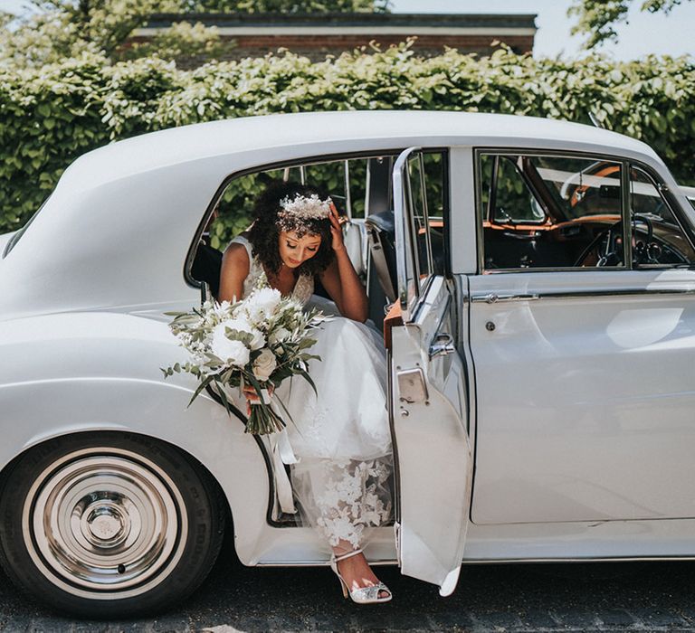 Bride leaves wedding car whilst holding floral bouquet 