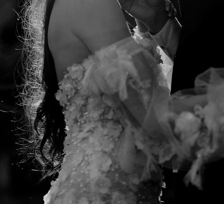 Bride in Pronovias wedding dress leans in toward her groom as the sun shines behind them in black & white image