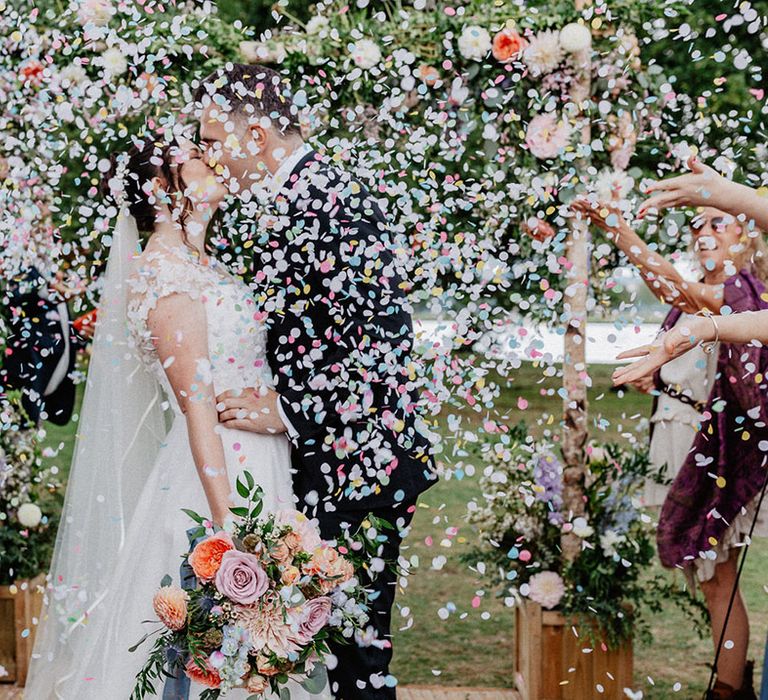 Colourful pastel wedding confetti moment for the bride and groom as they share a kiss at Culden Faw Estate