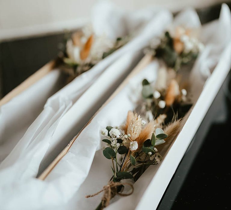 White flower and dried bunny grass buttonholes for the groom 