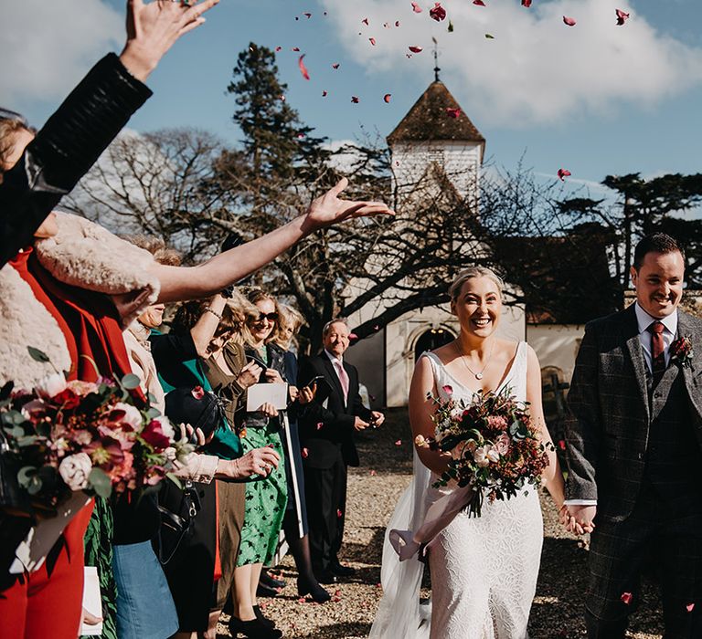 Bride and groom have fun confetti exit from their church ceremony 