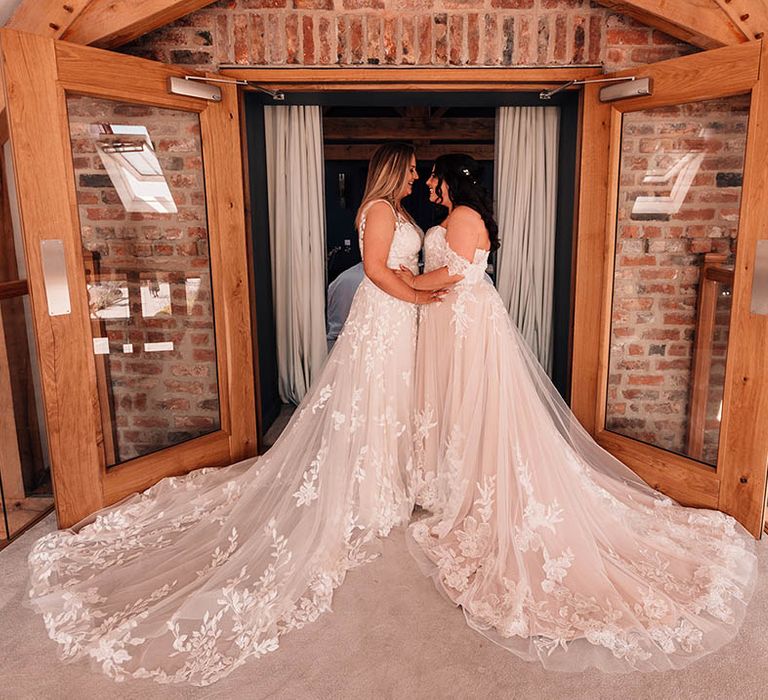 LGBTQIA+ wedding with the two brides in stunning lace wedding dresses embracing for a private first look moment 