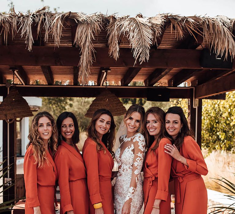 Bridesmaids in long sleeve orange wrap dresses posing with the bride for destination wedding in Ibiza 