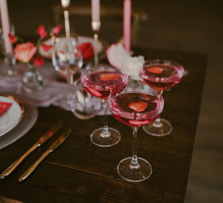 Pink wedding tablescape with pink candles, flowers, plates and drinks 