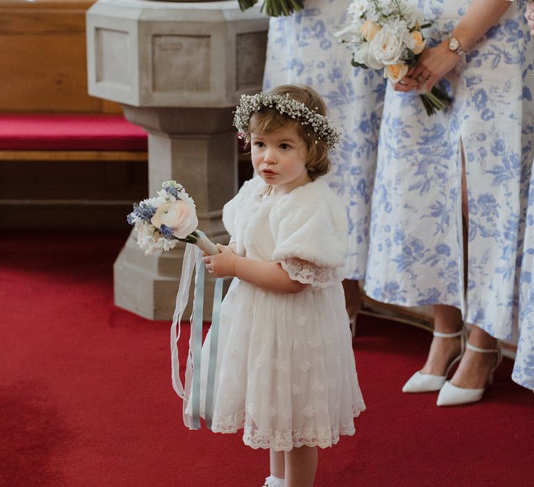 Flower girl in white dress with gypsophila flower crown and white faux fur shawl 