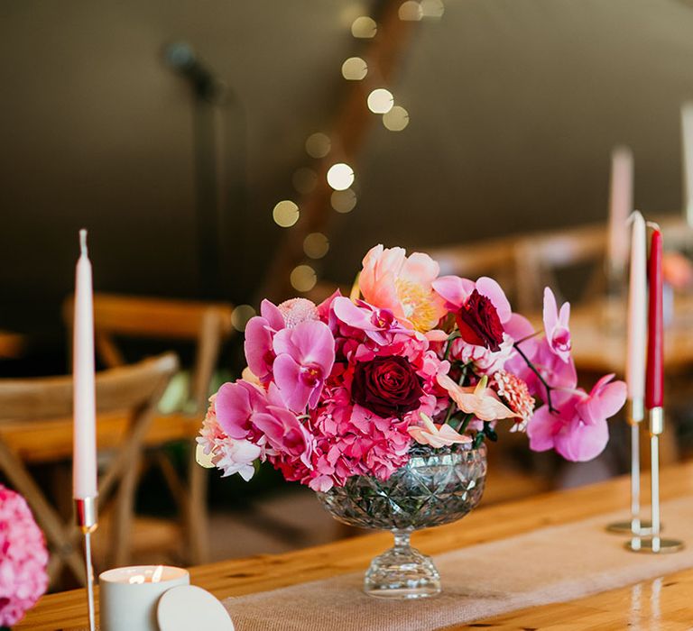 Bowl wedding table flower arrangement with roses, hydrangeas, and orchids with taper candles 