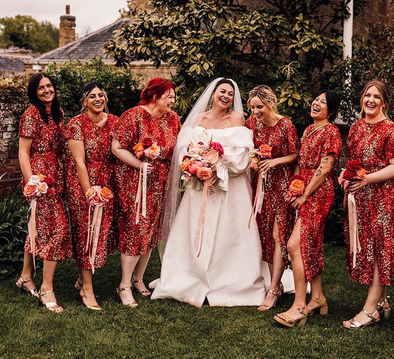 Bridal party wearing red sequin midi bridesmaid dresses with the bride in puff sleeve gown 