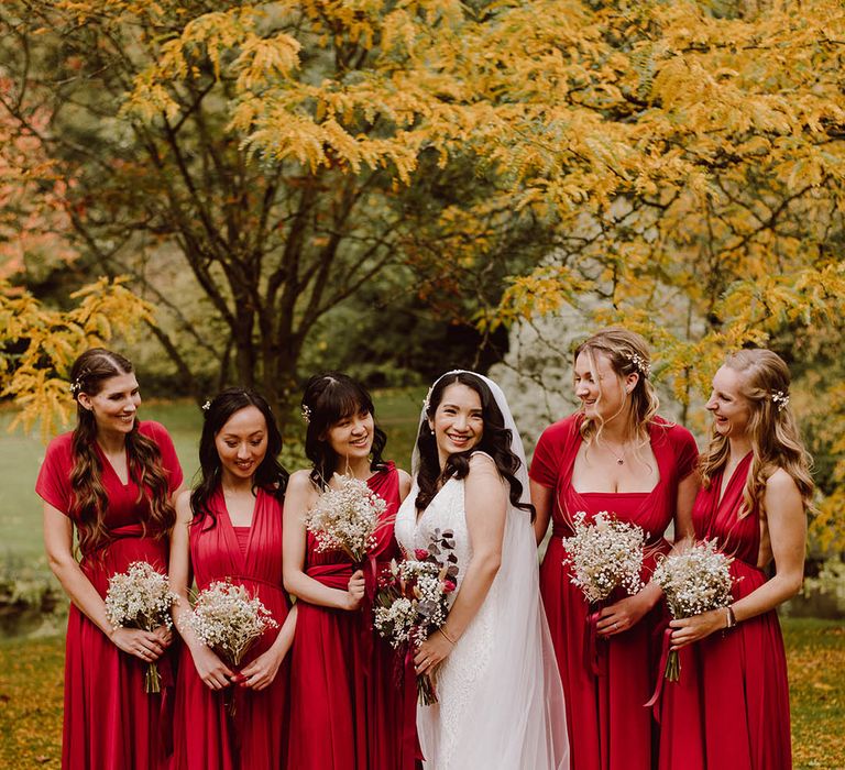 Bride in wedding dress with ombre wedding veil standing with bridal party in autumn bridesmaid dresses