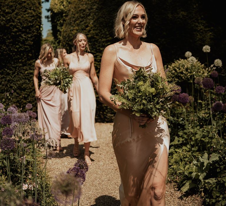 Bridesmaids holding green foliage bouquets in neutral dusky pink bridesmaid dresses 