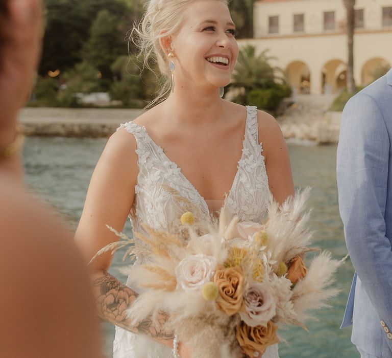 Swiss, blonde bride with bun wedding hairstyle wearing a lace wedding dress and holding a dried flower wedding bouquet 