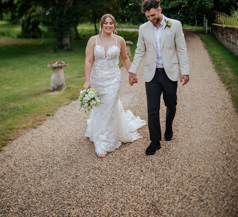 The bride and groom walk hand in hand at their contemporary wedding 