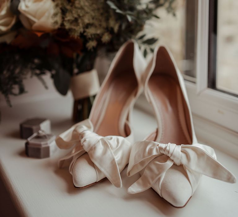 Bride wearing white pointed wedding shoes with white bow detail 