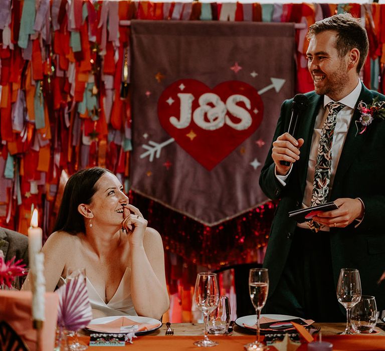 Custom purple banner wedding sign with the bride staring at the groom reading his wedding speech 