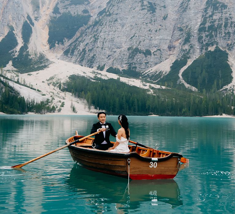 The bride and groom row out on the lake on a small boat 