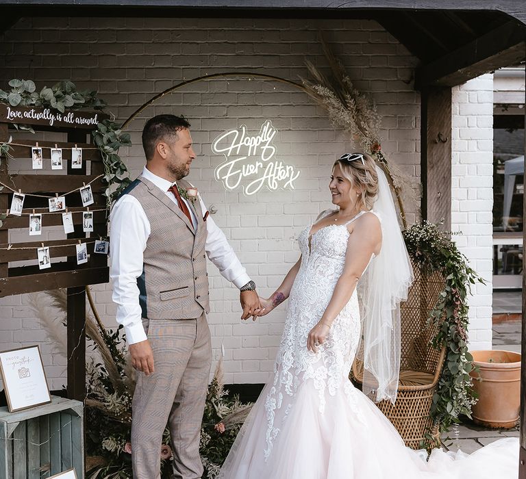 Neon wedding light sign backdrop with the bride and groom holding hands 