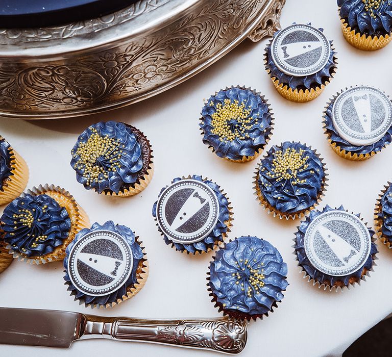 Dark blue icing on the cupcakes with some decorated by a personalised cupcake topper 