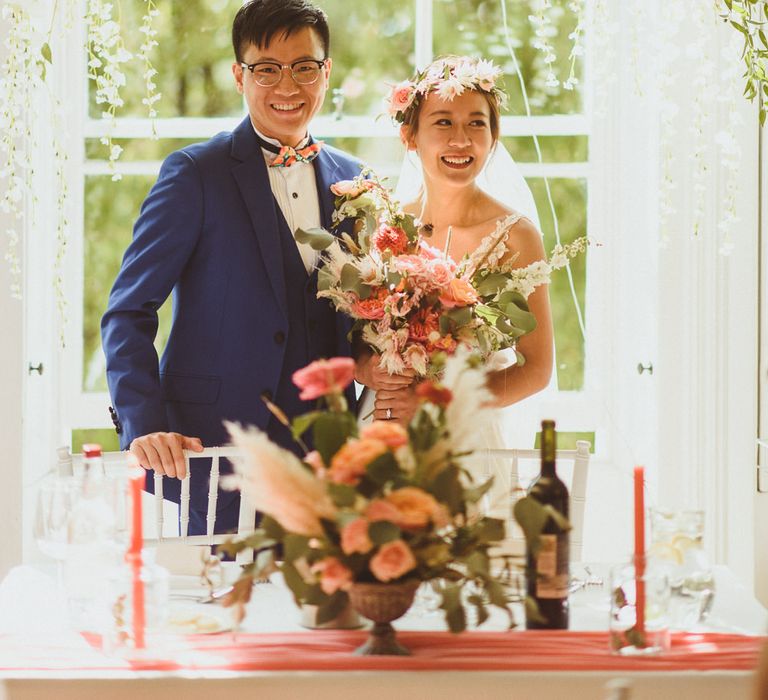 Bride and groom standing at their sweetheart table with floral arch backdrop