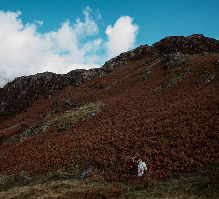 Bride and Groom walking through bracken in the Lake District