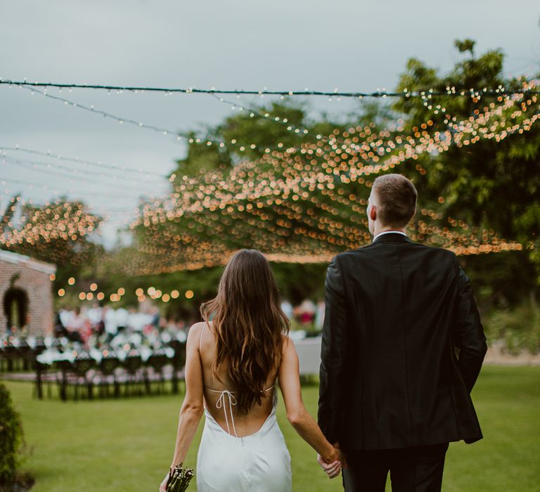 The bride and groom walk into their outdoor dance floor wedding reception