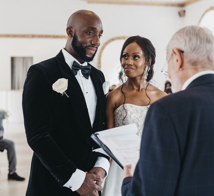 Black Bride and groom standing at the altar of Northbrook Park exchanging vows in a black tuxedo and strapless Oleg Cassini wedding dress