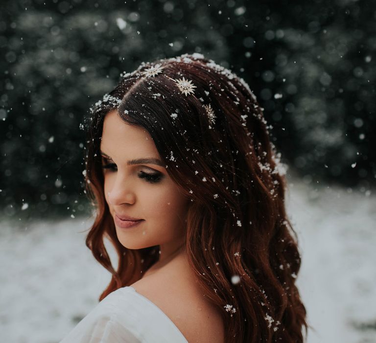 Bride with glam waves and celestial headband stands in snow at Cannon Hall