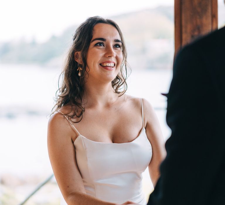 The bride smiling up at the groom as they say their vows